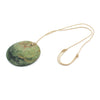 Disc Pounamu (Greenstone) pendant by Ric Moor on an adjustable cord against a white background